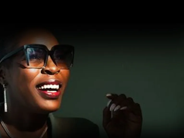 Low-key portrait of a laughing woman in sunglasses